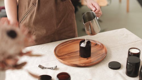 A Person Pouring Melted Wax in a Mold