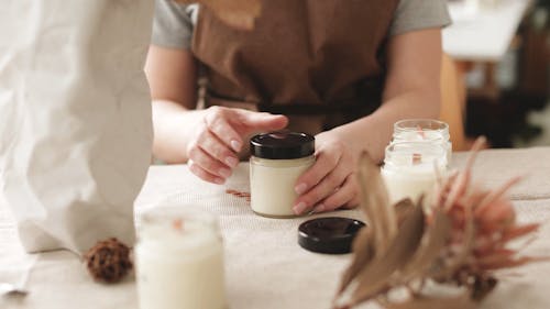 Person Opening the Lid of a Candle Jar