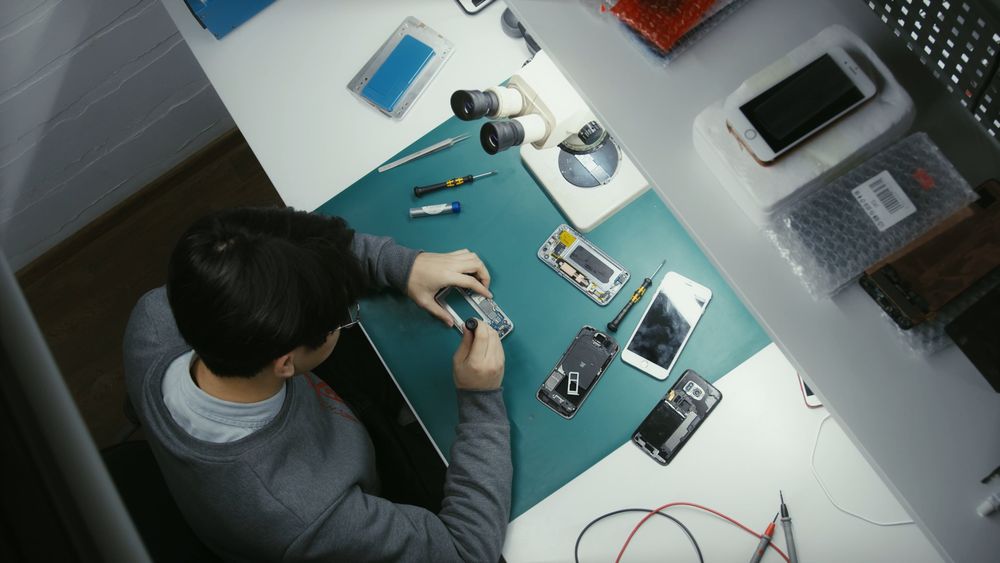 A technician repairing a smartphone at a workbench