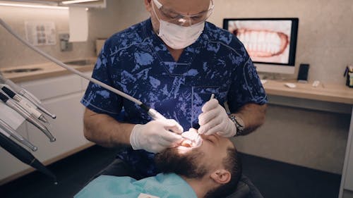 A Dentist Cleaning the Client's Teeth
