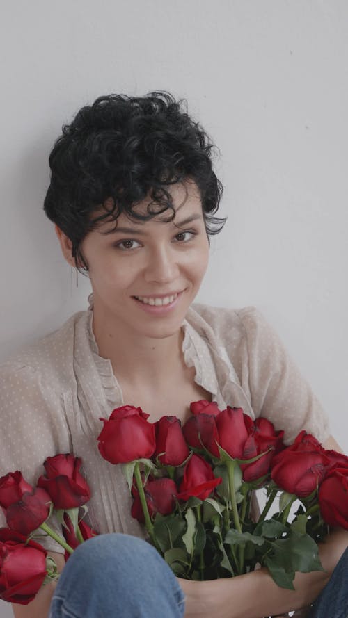 A woman Holding a Bunch of Red Roses While Sitting
