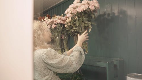 A Woman Placing the Pink Roses on the Vase at the Table