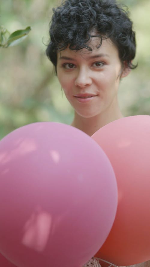 Woman Smiling while Holding Pink Balloons