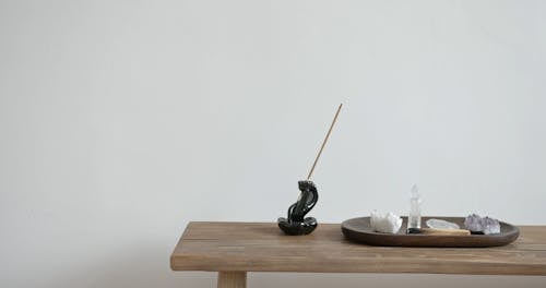 Person Placing Tibetan Singing Bowl on Wooden Table