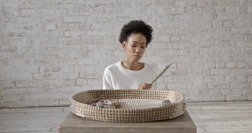 Woman Placing Herb Bundles on a Wicker Tray