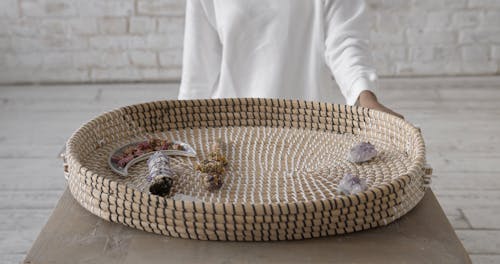 Woman Placing Herbal Smudge Sticks on a Wicker Tray