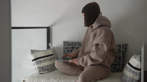 Woman in Brown Hoodie Using a Laptop