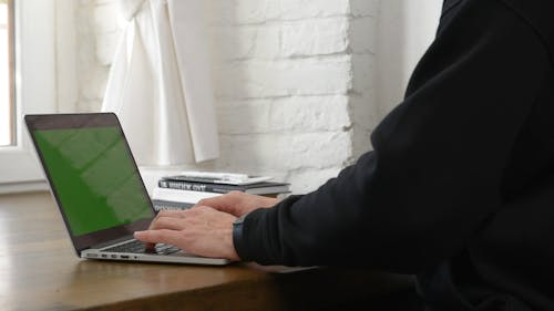 Man Typing on His Laptop While Sitting