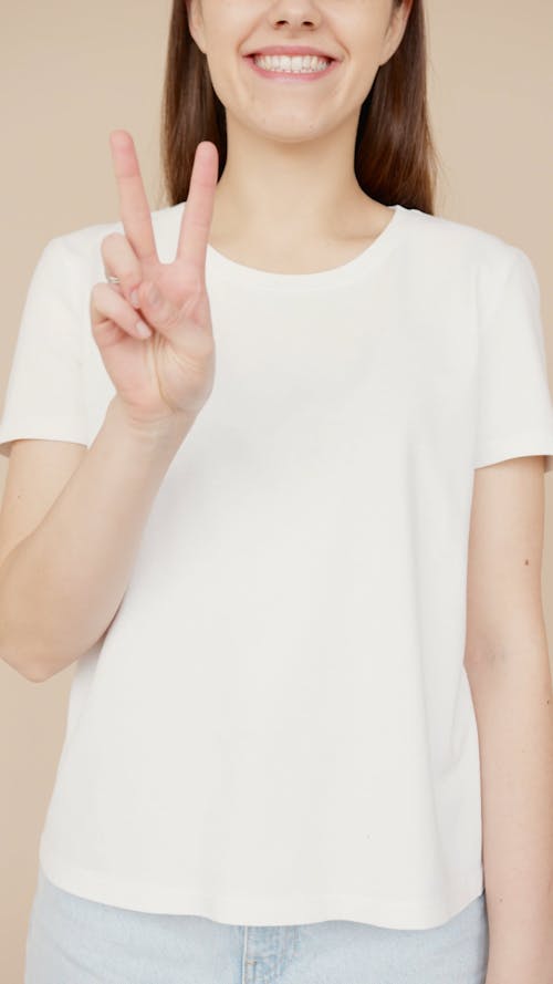 A Woman Wearing White Shirt while Doing Peace Sign