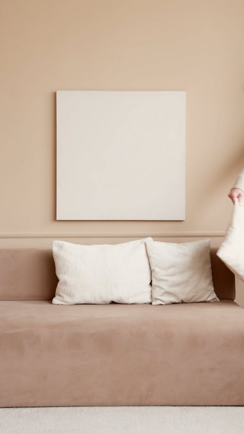 Person Placing Cushion On A Sofa