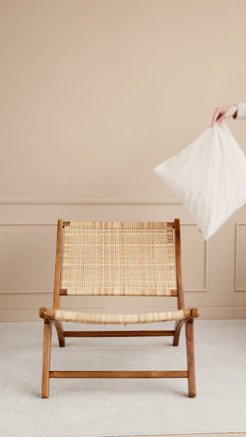 Person Placing Cushion On An Arm Chair