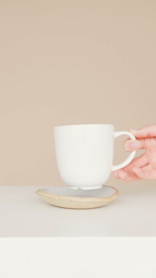 Person Placing Cup on a Saucer