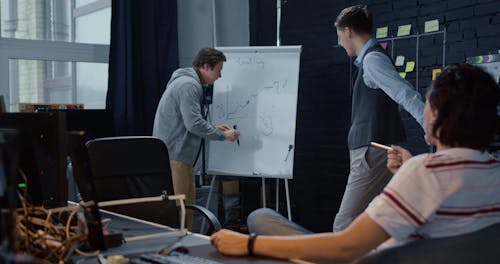 Colleagues Discussing Scheme on a Whiteboard