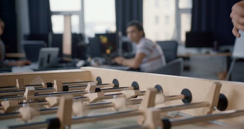 Men Playing Foosball and Working at the Office