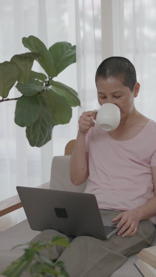 Woman Drinking Coffee while Using Her Laptop