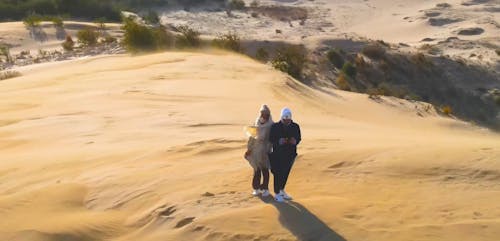 Two People Standing on Top of Sand Dune