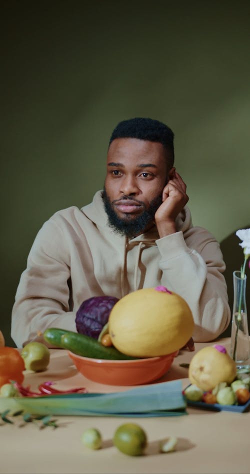 Man Sitting in Front of Fruits and Vegetables