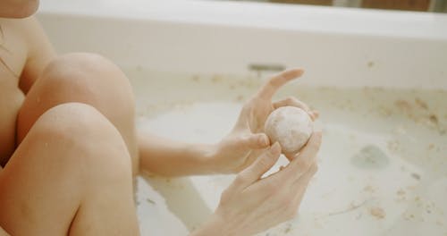 Woman Holding Bath Bomb Inside Bathtub