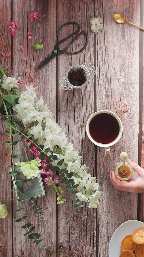 A Person Mixing Honey on a Cup of Tea then Drinking 