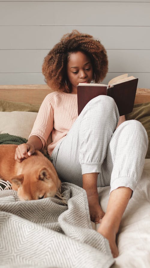 Woman Caressing A Dog While Reads A Book
