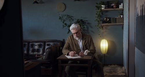 A Grey Haired Man Writing a Letter