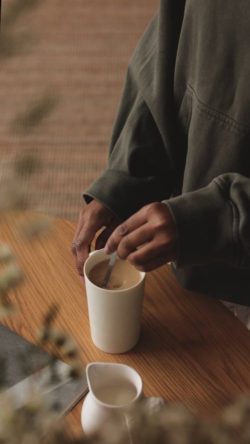 A Faceless Person Stirring Coffee