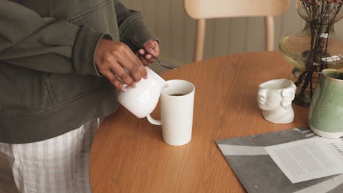 A Person Pouring Milk into a Cup of Coffee