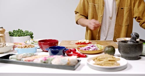 A Person Wrapping Tofu and Vegetables with Rice Paper