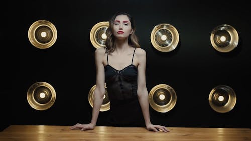 A Woman Posing while Leaning on a Table