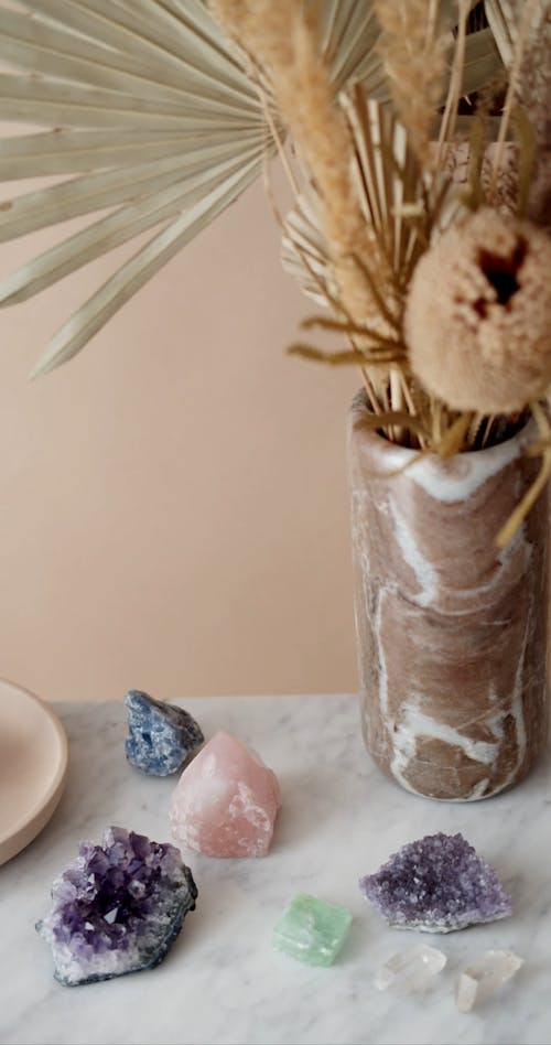 A Woman Putting Crystals Beside a Flower Vase