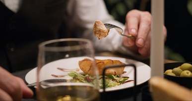 a man eating bread while a woman is getting a mussel from the bowl