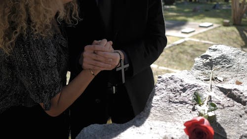 A Couple Holding Hands During the Funeral