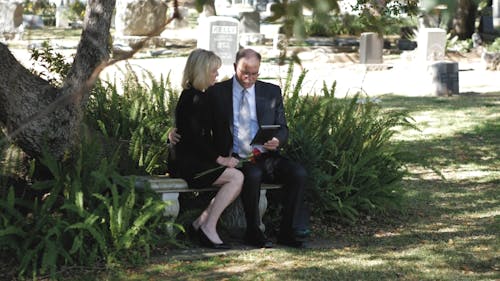 Elderly Couple Sitting on a Bench in the Cemetery