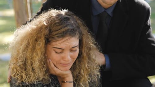 Couple Grieving In Front of A Grave