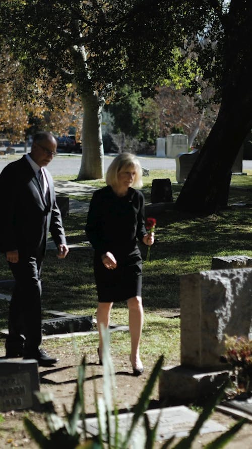 Woman Putting Flower on Top of a Gravestone