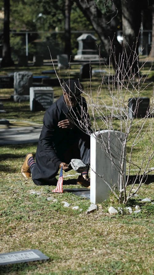 Man Kneeling in Front of a Gravestone