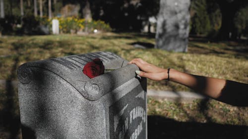 A Person Grieving In Front of A Grave