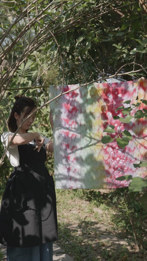 A Young Woman Hanging a Piece Fabric Outside