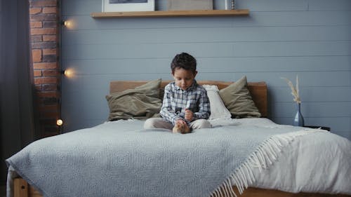 A Boy Petting a Rabbit in the Bed