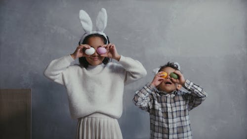 Children Playing with Easter Eggs while Wearing Easter Bunny Headbands 