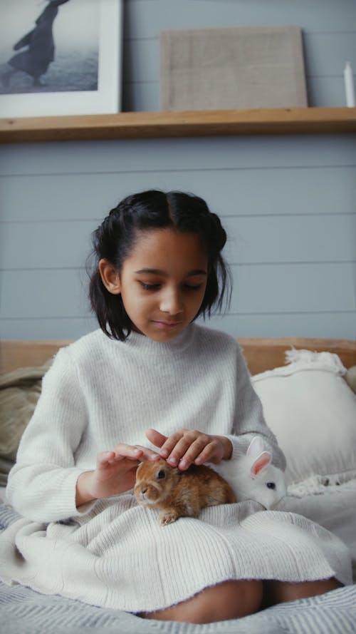 A Girl Petting Rabbits in the Bed