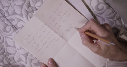 A Person Writing a Love Letter And Putting it in an Envelop