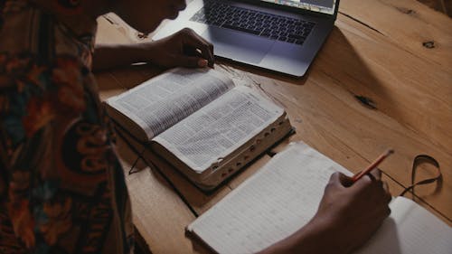 Person Reading the Bible while Writing