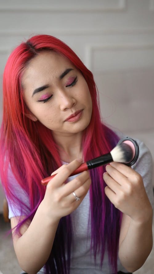 Woman Applying Blush on Her Face Using a Brush