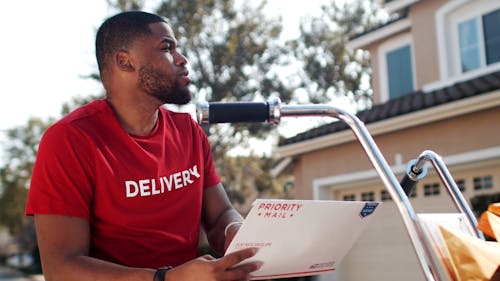 A Man Holding an Envelope while Riding a Bike