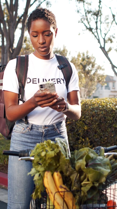 Delivery Woman Checking Her Phone for Delivery Details