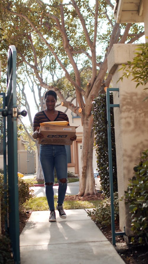 A Woman Going Through a Gate while Carrying Parcels