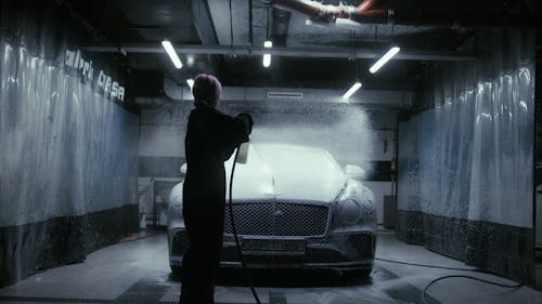 A Woman Splashing Soap on the Black Bentley 