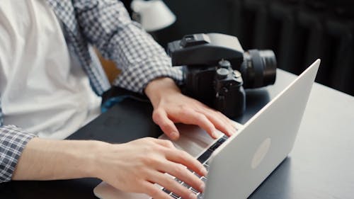 A Faceless Person Typing on a Laptop