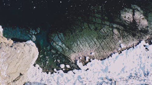 Drone Footage of a Snow Covered Cliff and an Icy Shoreline